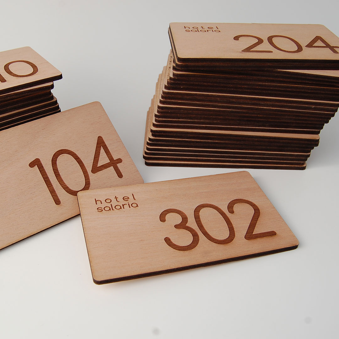 Cartelli rettangolari in legno compensato okumè numerati per stanze hotel.